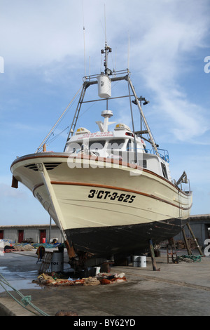 La pesca a strascico in riparazione nel porto di Javea danneggiate seguenti scafo inferiore Foto Stock