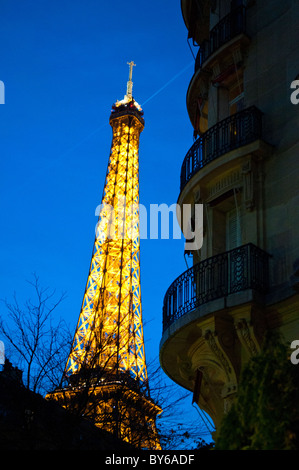 Torre Eiffel struttura in ferro illuminata luci d'oro Searchlight Parigi Francia // PARIGI, Francia - la Torre Eiffel, un'iconica struttura a reticolo di ferro, è illuminata da luci dorate e da uno scintillante display, con un fascio di luce mirata contro il cielo notturno. Faro nel paesaggio notturno parigino, è stato progettato da Gustave Eiffel per l'esposizione universale del 1889. La torre è alta 330 metri (1.083 piedi), inclusa l'antenna. Situato sul Champ de Mars a Parigi, Ile-de-France, è un'icona culturale globale della Francia. È uno dei monumenti a pagamento più visitati al mondo. Foto Stock