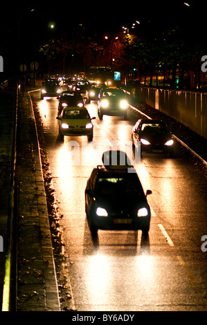 Traffico notturno su strada bagnata 7° Arrondissement Parigi Francia | PARIGI, Francia — I fari si estendono sull’asfalto bagnato di una strada scivolosa per la pioggia nel 7° arrondissement, il quartiere della Rive Gauche che circonda la Torre Eiffel e il Champ de Mars. Il quartiere ospita anche numerosi ministeri governativi e musei, rendendolo uno dei quartieri amministrativi e culturali più importanti della capitale. Foto Stock