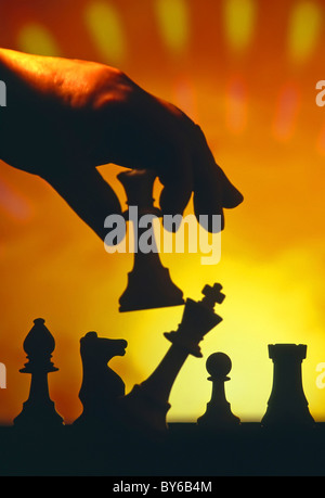 Stretta di mano e le dita tenendo la silhouette pezzo degli scacchi in un gioco o sport creati come ancora un'immagine di vita in studio di impostazione England Regno Unito Foto Stock