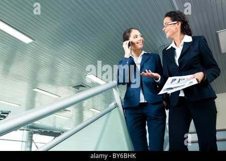 Foto di business ladies camminare al piano di sotto e parlare con ciascun altro Foto Stock