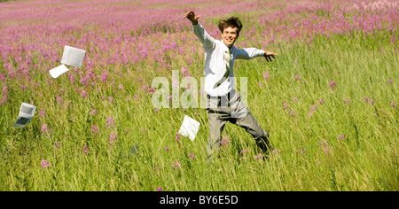 Foto di happy businessman in esecuzione su campo verde sulla giornata di vento in estate Foto Stock