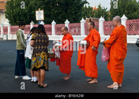 I monaci la ricezione di elemosina dal merito-makers nella parte anteriore del Wat Benjamabophit, Bangkok, Thailandia Foto Stock
