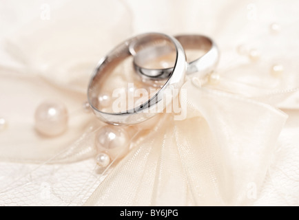 Coppia di nozze d'oro anelli su invito decorate con seta bow & Pearls Foto Stock