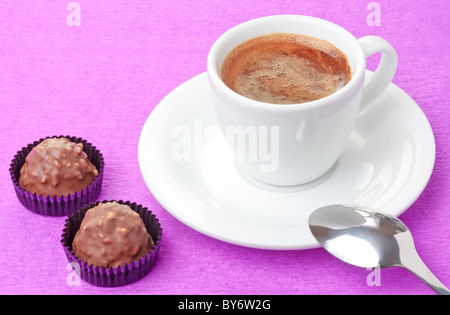 Preparato di fresco caffè caldo in tazza bianca e cioccolato al latte dolci con scaglie nocciola su sfondo rosa Foto Stock