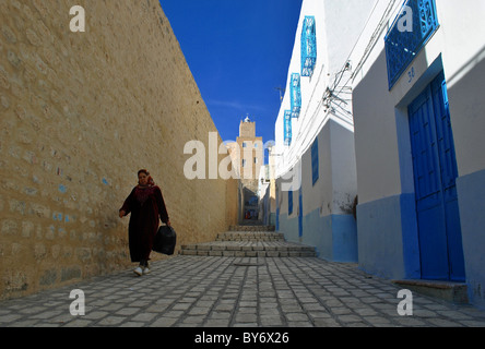 Donna che cammina giù per una strada in Sousse medina, Tunisia Foto Stock