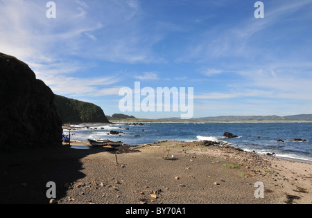 Cielo blu vista entroterra di 3 barche di pescatori sulla spiaggia di una piattaforma sotto rocce basaltiche, Mar Brava, Pacific Coast, Isola di Chiloe, Cile Foto Stock