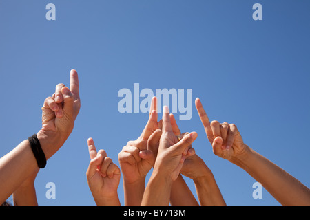 Molte le mani alzate verso il cielo blu (alcune sfocature) Foto Stock