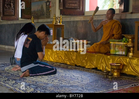 Un monaco buddista è in possesso di una tradizionale cerimonia di ALMS con due donne in un bellissimo tempio in Nong Kai, Thailandia. Foto Stock
