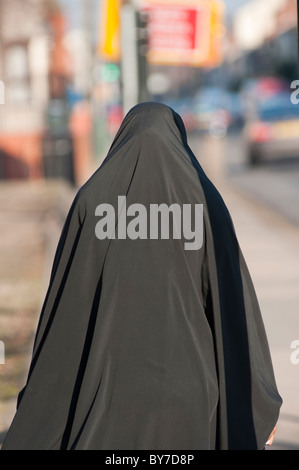 Una donna musulmana di indossare il burka cammina giù Stoney Stanton Rd di Coventry, West Midlands, Inghilterra Foto Stock