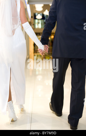 Lo sposo e la sposa a piedi in un centro commerciale, mano nella mano Foto Stock