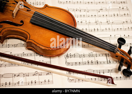 Vecchio violino e archetto su note musicali da vicino Foto Stock