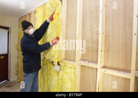 Workman installazione di rockwool isolamento termico nelle cavità del legno a parete, REGNO UNITO Foto Stock