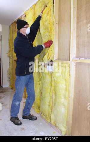 Workman installazione di rockwool isolamento termico nelle cavità del legno a parete, REGNO UNITO Foto Stock