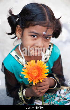 Sorridente piuttosto giovane ragazza indiana holding orange gerbera fiore. Andhra Pradesh, India. Messa a fuoco selettiva. Foto Stock