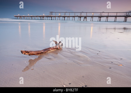 Legno sulla spiaggia con pier in background Foto Stock