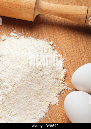 Farina e uova su una tavola di legno Foto Stock