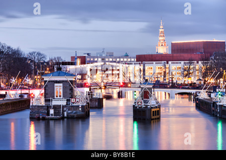 Amsterdam Amstel River con skinny ponte Magere Brug e Muziektheater, Opera House al tramonto in inverno. Foto Stock