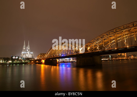 La cattedrale di Colonia con ponte di Hohenzollern di notte Foto Stock