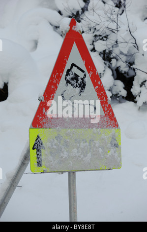 Cartello stradale avverte di scivolosa la neve e il ghiaccio sulla strada Foto Stock