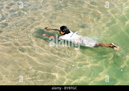 Donna messicana indossare gonna & tee shirt nuotare nel mare trasparente bassifondi off Puerto Angel beach Stato di Oaxaca Messico Foto Stock