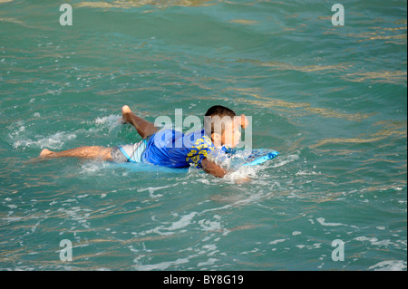 Ragazzo giovane imparare a navigare sulla spiaggia di Waikiki Hawaii Honolulu Oahu Oceano Pacifico Foto Stock