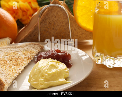 La prima colazione che mostra toast, burro, marmellata e succo di arancia Foto Stock