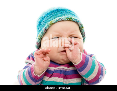 Testa e spalle hanno girato di Baby in un abito colorato e brillante e cappello turchese che scrunching è il viso. Foto Stock