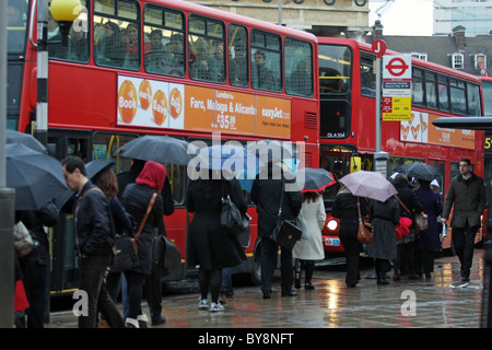 In una coda di attesa di persone sotto la pioggia a bordo di un autobus di Londra di mattina ora di punta a Waterloo, Londra Foto Stock