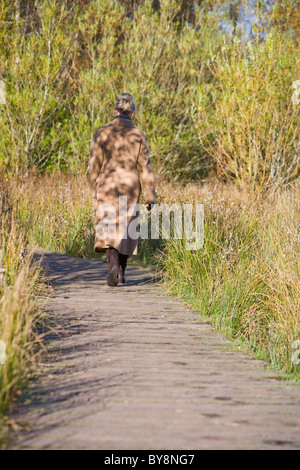 Donna che cammina NEL REGNO UNITO IL PARCO IN INVERNO Foto Stock