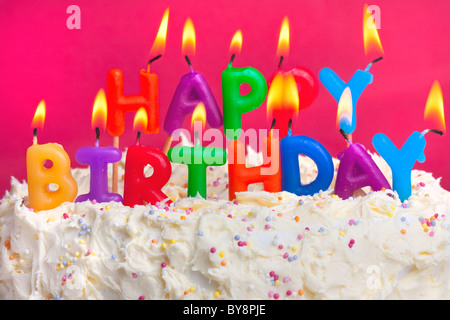 Colorato acceso candele spellign fuori buon compleanno su una torta Foto Stock
