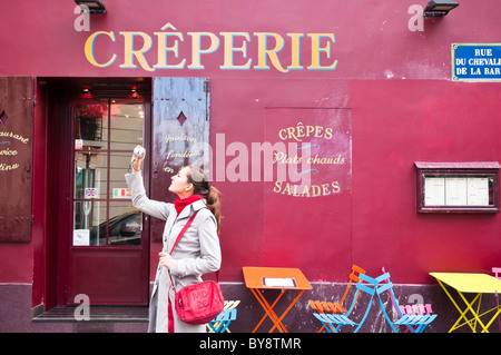 Una giovane donna di fare una foto con un punto e scattare foto fotocamera vicino alla Place du Tertre, Montmartre, Parigi, Francia