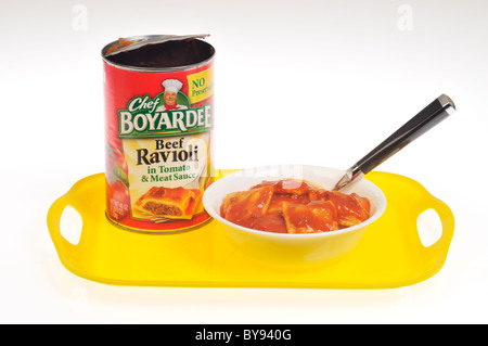 Ciotola di Chef Boyardee Ravioli di carne in una ciotola bianca con lattina vuota sul vassoio giallo su sfondo bianco, tagliate Foto Stock