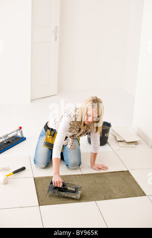 Home Improvement, ristrutturazione - handywoman posa di piastrelle, frattazzo con malta Foto Stock