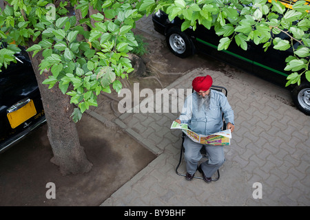 La religione sikh taxi driver leggendo il giornale Foto Stock