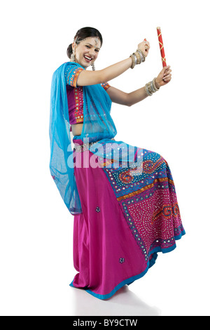 Gujarati woman dancing con bastoni dandiya Foto Stock