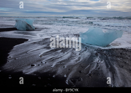 Mare lappatura su blocchi di ghiaccio sulla spiaggia, Joekulsarlon, Islanda, Europa Foto Stock