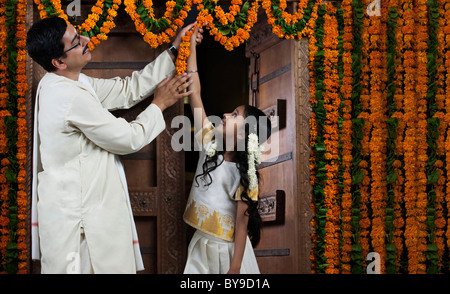 Sud indiane uomo aiutando la figlia decorare Foto Stock