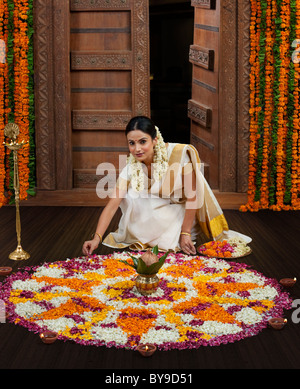 Sud donna indiana rendendo un fiore rangoli Foto Stock