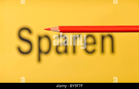 Matita rossa nella parte anteriore del fuori fuoco parola Sparen, tedesco per il salvataggio Foto Stock