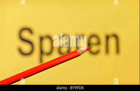 Matita rossa nella parte anteriore del fuori fuoco parola Sparen, tedesco per il salvataggio Foto Stock