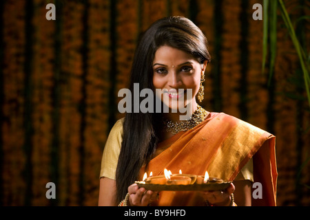 Donna che mantiene un vassoio con diyas Foto Stock