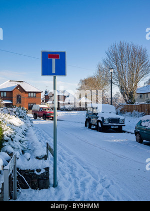 Un no attraverso il cartello stradale in inglese villaggio circondato da neve. Wrington, North Somerset, Inghilterra. Foto Stock