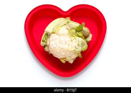 Foto concettuale di un cavolfiore nel cuore un piatto sagomato per rappresentare un amore del vegetale, isolato su sfondo bianco Foto Stock