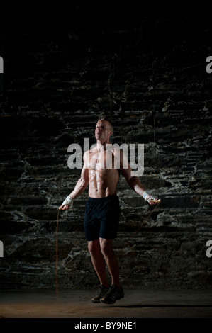 Una adatta fisicamente uomo esercitando con un salto con la corda Foto Stock