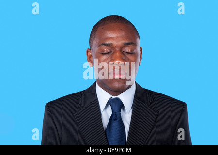 Imprenditore africani con i suoi occhi chiusi (isolato su blu) Foto Stock