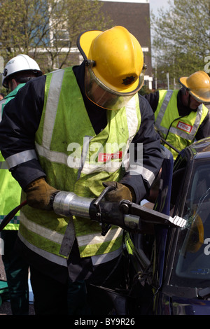 I vigili del fuoco utilizzando strumenti di soccorso a una scena di crash Foto Stock