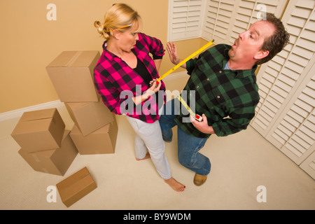 Coppia avente una spada divertente lotta con loro le misure lineari a nastro circondato da pranzo spostando le caselle. Foto Stock