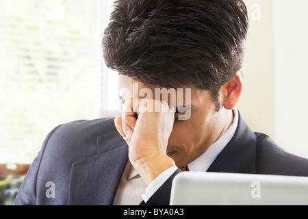 Imprenditore ottenere un mal di testa in ufficio Foto Stock