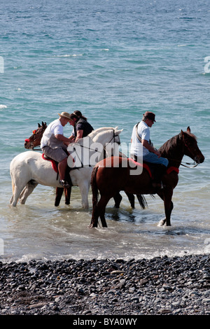 Piloti la balneazione i loro cavalli in mare a Adeje come parte dell'fiestas de San Sebastian, Tenerife, Isole Canarie, Spagna Foto Stock